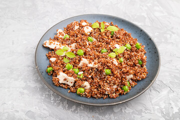 Quinoa porridge with green pea and chicken on ceramic plate on a gray concrete background. Side view.