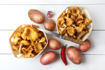 Raw chanterelles, potatoes, garlic and chili on a white table