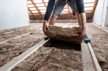 Man insulating the attic with rock wool.