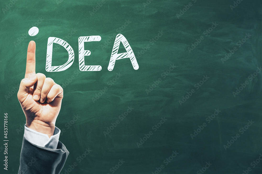 Poster Hand pointing up replacing letter i in idea word on chalkboard background with mock up place. Inspiration and creativity concept.