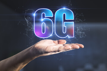Man hand holding abstract glowing 6G hologram on dark blurry background. Internet, technology and communication concept.