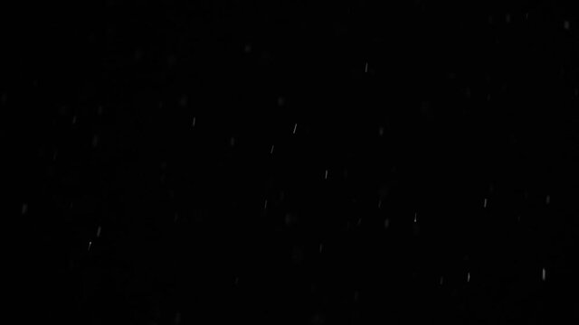 Bokeh of white snow on a black background hd slow motion video. Falling snowflakes on night sky background, isolated for post production and overlay in graphic editor.