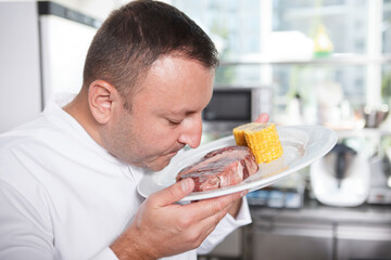 Close up of a professional chef smelling beef steak before cooking it