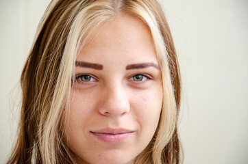 Brunette ith white strands of hair girl looks at camera and smiles. Happy young woman. Beautiful caucasian young girl with green eyes. Acne on skin. Student, entrant or employee. Concept of beauty.