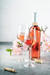 Rose wine glass and bottle on the gray table and pink flowers. Rosado, rosato or blush wine tasting