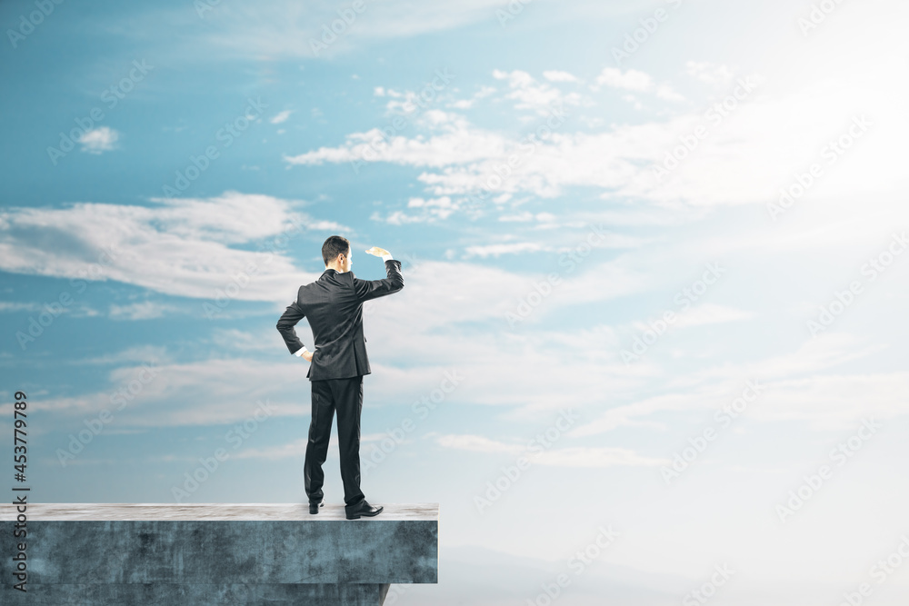 Poster businessman on abstract concrete edge looking into the distance on creative bright sky background wi