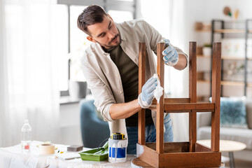 renovation, diy and home improvement concept - man degreasing old wooden table or chair surface...
