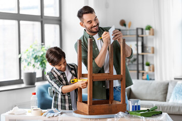 family, diy and home improvement concept - happy smiling father and son with ruler measuring old...