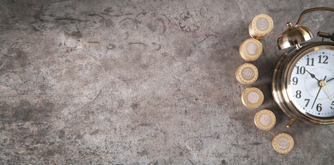 Stack of coins with alarm clock.