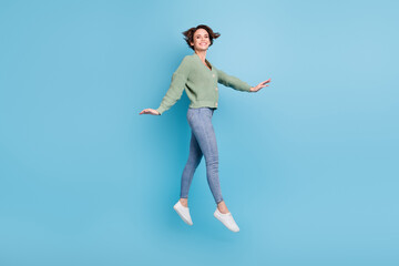 Obraz premium Full length photo of funky adorable young girl dressed green cardigan jumping high isolated blue color background