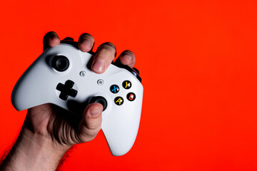 A photo of a man hand clutching a white gamepad on a bright red background with a place for the...