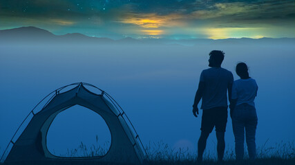 The man and woman standing on a mountain top at the campsite - Powered by Adobe