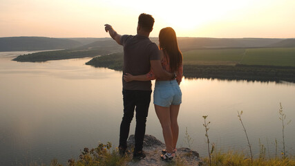 The romantic couple stand on mountain top on the beautiful river background
