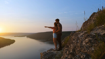 Obraz premium The young couple standing on rocky mountain above the beautiful river