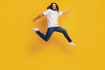 Portrait of active crazy funky guy run fast hurry jump on yellow background