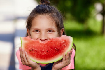 child girl eats a watermelon in sunny day