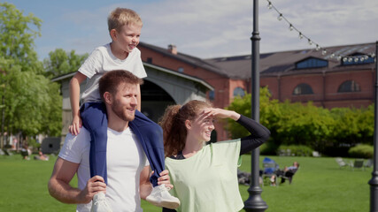 Happy young mother, father and son in sportswear relaxing in park