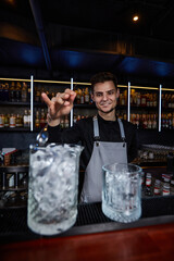 Barman stirring ice cubes in cocktail glass with spoon
