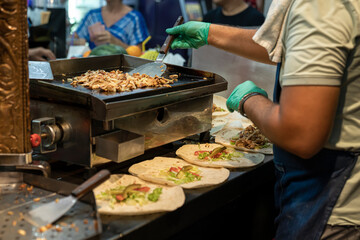 Preparation of Turkish shawarma. the cook's hands in rubber gloves apply a delicious chopped fried chicken meat with a spatula to put it into cakes with shawarma. street food, fast real life