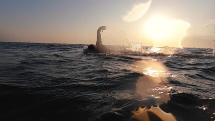Professional swimmer at open sea. Epic sunset swim slow motion shot