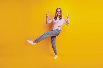 Fototapeta na wymiar Photo of friendly cheerful girl stand one leg show v-signs on yellow background