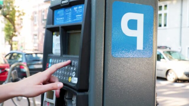 A woman pays in the parking lot for parking 