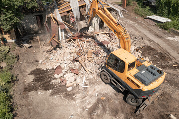 Demolition of old house building process for new construction by excavator bucket, aerial view....