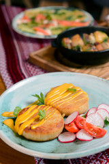 Grilled burgers with sauce and vegetable radish salad on a plate on a rustic wooden table background.