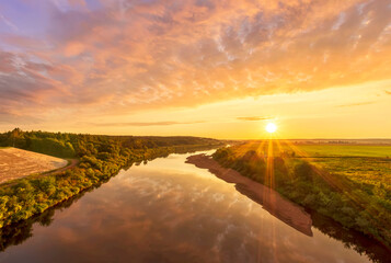 amazing view at beautiful summer river sunset, halo with reflection on water with green bushes,...