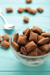 Bowl with chocolate pads on blue background. Vertical photo