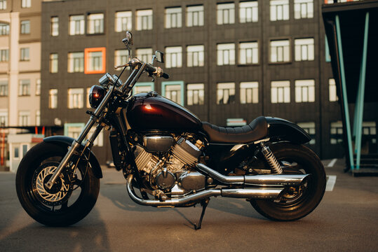 Kyiv, Ukraine, 07 July 2021. A motorcycle in a parking lot in the warm light of a sunset. Stylish custom chopper motobike with chrome details