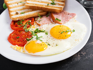 Fried eggs with ham, tomatoes and toasts. Delicious English Breakfast. Brunch.