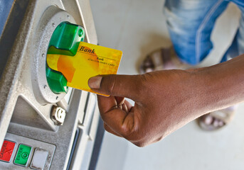 Close up of human hand inserting Credit/Debit card into ATM machine slot