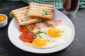 Fried eggs with ham, tomatoes and toasts. Delicious English Breakfast. Brunch.