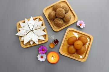 Diwali Diya, Sweets or Mithai, and flowers are arranged as a festive background. assorted sweets...