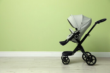 Baby carriage. Modern pram near light green wall, space for text © New Africa