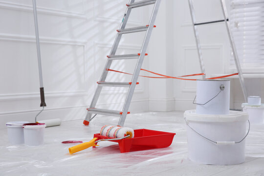 Metal stepladder, buckets of paint and renovation tools indoors