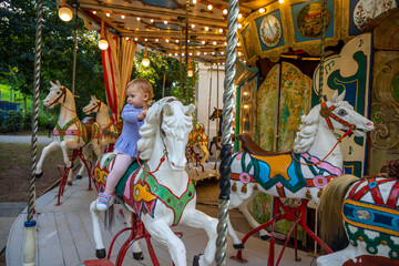 Fototapeta na wymiar Cute baby girl on the horse of old retro carousel, Prague, Czech republic 