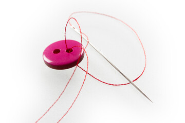 two thread holes, pink button, needle and thread