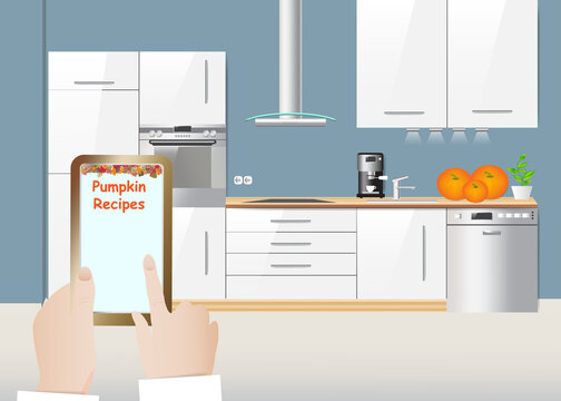 Hand holding smartphone with pumpkin recipes. White kitchen interior with equipment is in the background.