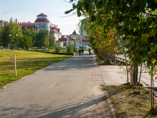 Noyabrsk, Russia - august 30, 2020: People walk along the city path in the city center. An alley with trees is planted along the street