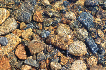 Abstract background: the orange and gray stones in pure transparent mountain river water, Magadan region
