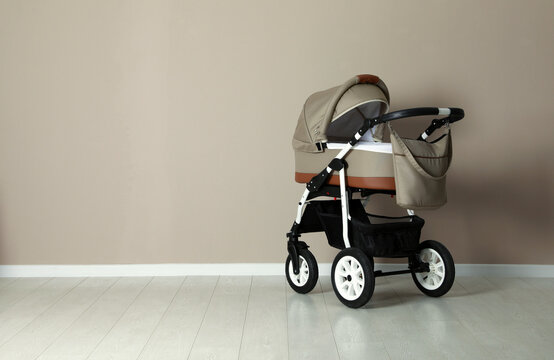 Baby carriage. Modern pram near beige wall, space for text