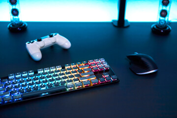 Clean workplace of gamer. Various color backlighted gaming accessories on grey desk.