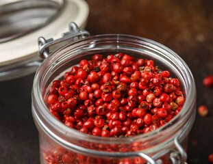 Red Peppercorns in glass jar on wooden table