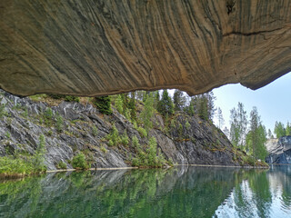 View from the grotto with a textured ceiling on the steep slope of the flooded Marble Canyon in the Ruskeala Mountain Park on a sunny summer day.