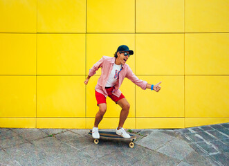 middle-aged man wearing a cap, enjoying a skateboard on a yellow background