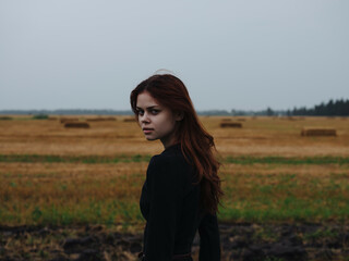 woman in black dress in the field red hair posing rest