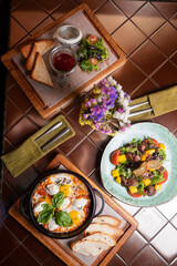 Shakshuka breakfast in an iron pan. Fried eggs with tomatoes, toast, meat salad and juice. Healthy eating.