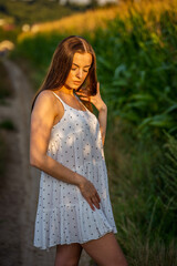 Fototapeta na wymiar Young beautiful woman in white dress in corn field.